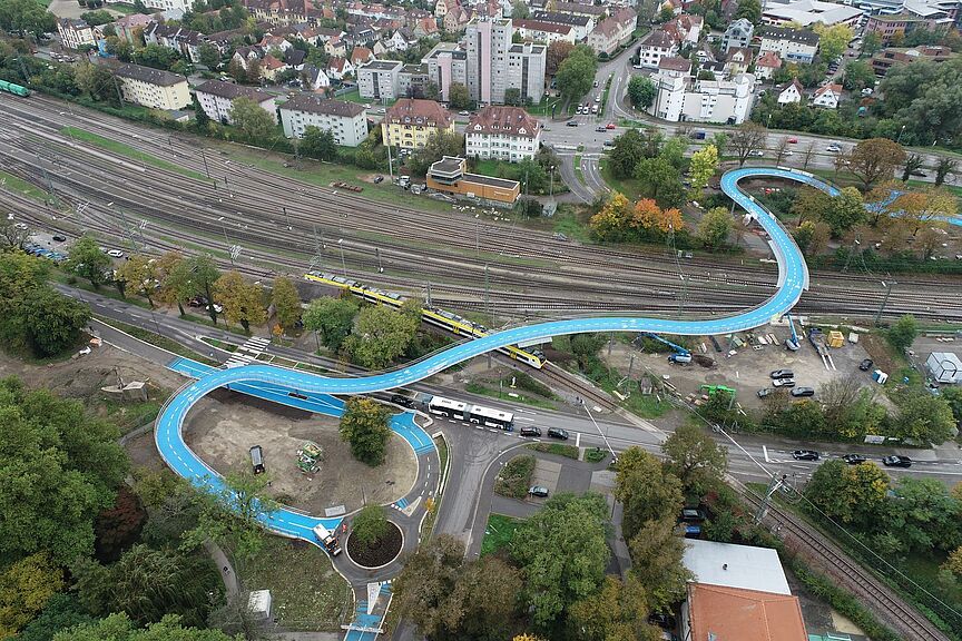 Ann Arbor Bridge Tübingen Luftbild der Ann Arbor Bridge mit hellblauer Fahrbahn, die sich über Bahngleise in Tübingen schlängelt.